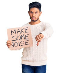 Handsome latin american young man holding make some noise banner with angry face, negative sign...