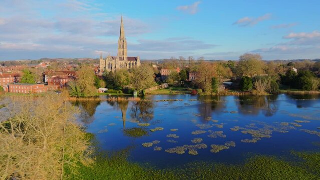 Aerial shot flying over flooded fields with reflective water and Salisbury Cathedral in background