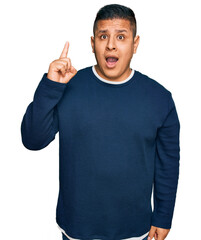 Young latin man wearing casual clothes pointing finger up with successful idea. exited and happy. number one.