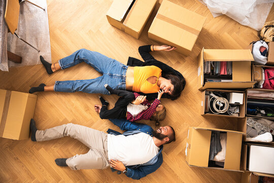 Top view of a family with a child moving to a new house with cardboard boxes on the ground