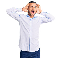 Young handsome man wearing business clothes smiling cheerful playing peek a boo with hands showing face. surprised and exited