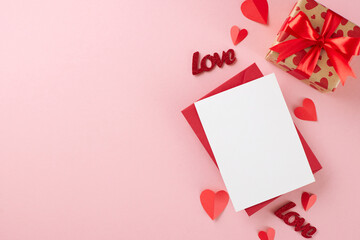 Valentine's day gift inspiration. Top view composition of red envelope with card, gift box, paper hearts on pastel pink background with advert panel