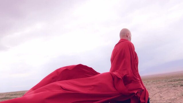 A monk in red prays in the steppe. A divine ritual.