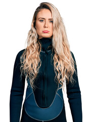 Young blonde woman wearing diver neoprene uniform depressed and worry for distress, crying angry...