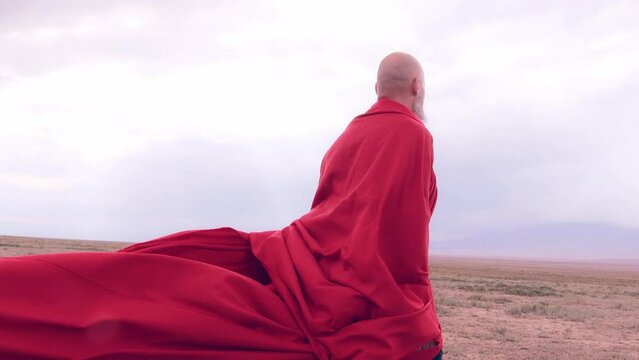 A monk in red prays in the steppe. A divine ritual.