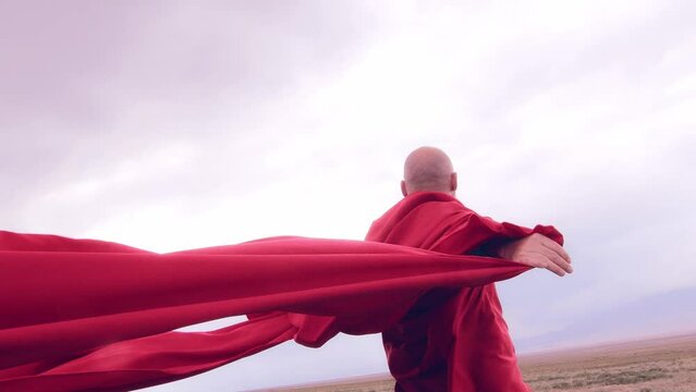 A monk in red prays in the steppe. A divine ritual.