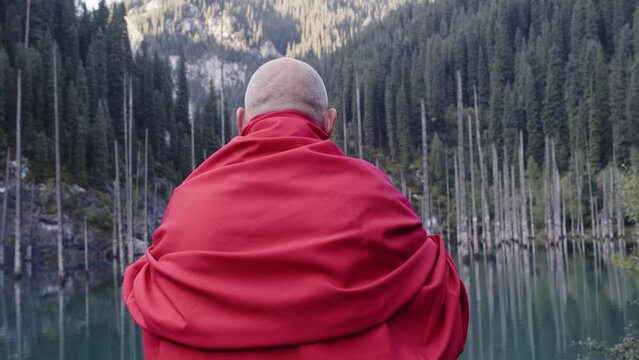 A monk in red prays in the steppe. A divine ritual.
