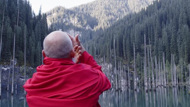 A monk in red prays in the steppe. A divine ritual.
