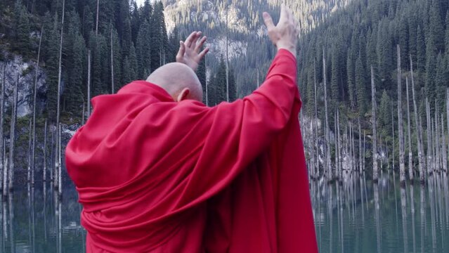 A monk in red prays in the steppe. A divine ritual.