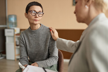 Portrait of mature woman in consultation with mental health therapist comforting her, copy space