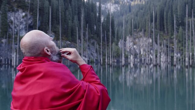 A monk in red prays in the steppe. A divine ritual.