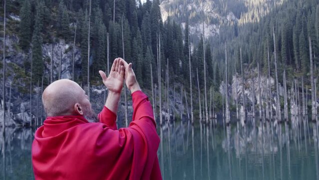 A monk in red prays in the steppe. A divine ritual.