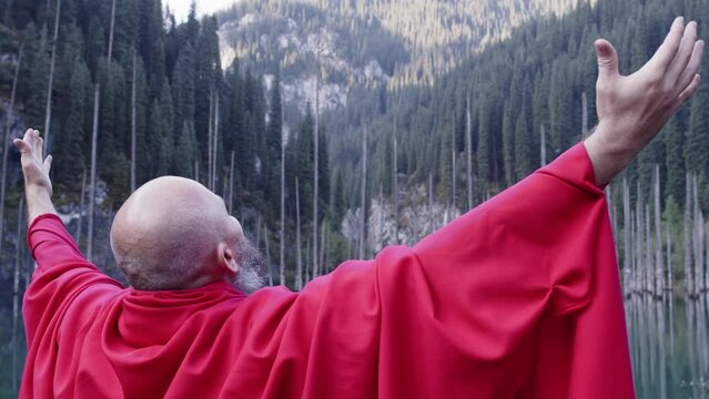 A monk in red prays in the steppe. A divine ritual.
