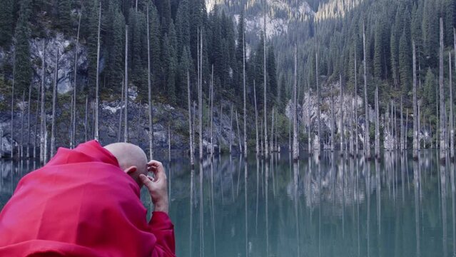 A monk in red prays in the steppe. A divine ritual.