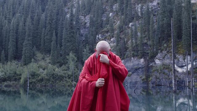 A monk in red prays in the steppe. A divine ritual.