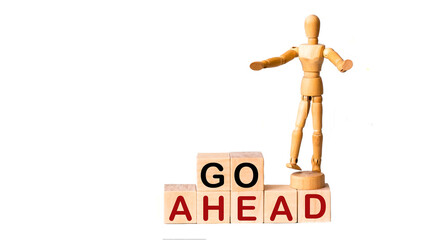 Go ahead text image on wooden blocks and a white background, next to a wooden doll