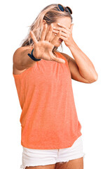 Middle age fit blonde woman wearing casual summer clothes and sunglasses covering eyes with hands and doing stop gesture with sad and fear expression. embarrassed and negative concept.