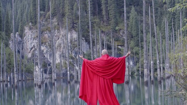 A monk in red prays in the steppe. A divine ritual.