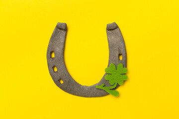 Metal horseshoe with clovers on color background, top view. St. Patricks day concept