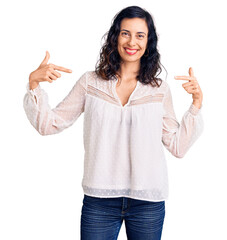 Young beautiful hispanic woman wearing casual clothes looking confident with smile on face, pointing oneself with fingers proud and happy.