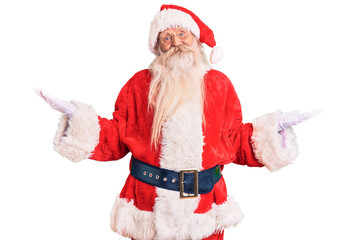 Fototapeta na wymiar Old senior man with grey hair and long beard wearing traditional santa claus costume smiling showing both hands open palms, presenting and advertising comparison and balance