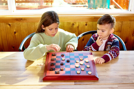 Two kids play games on a table in the woods