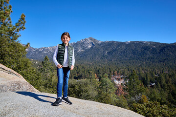 A young girl stands on a rock with a mountain behind