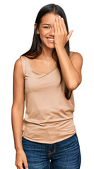 Obraz premium Beautiful hispanic woman wearing casual clothes covering one eye with hand, confident smile on face and surprise emotion.