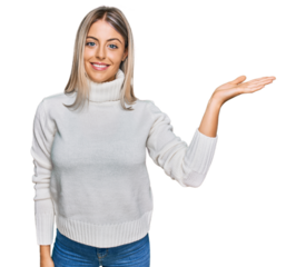Beautiful blonde woman wearing casual turtleneck sweater smiling cheerful presenting and pointing with palm of hand looking at the camera.