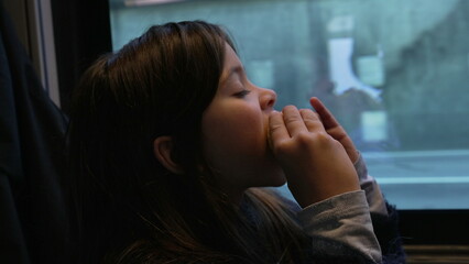 One small girl eating corn while inside a moving train. Child snacking healthy food while scenery...