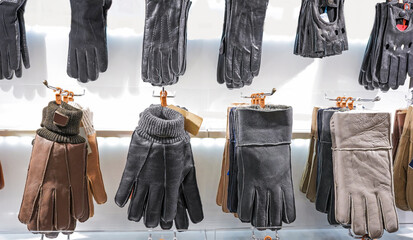 Winter leather gloves, of different colors, hang on a rack in a store, on a market for buyers.