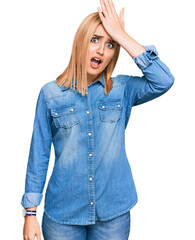 Beautiful caucasian woman wearing casual denim jacket surprised with hand on head for mistake,...