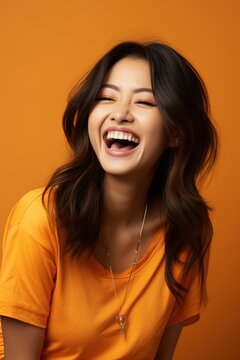Laughing woman with long dark hair wearing an orange shirt