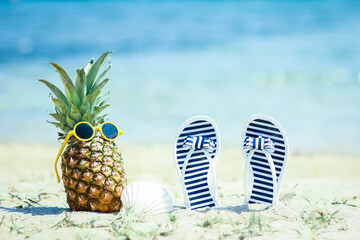 A Pineapple in nature by the sea with sneakers on the shore nature background - obrazy, fototapety, plakaty