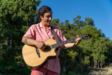 Young man playing guitar in the backyard on a beautiful summer day.