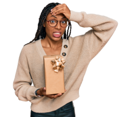 African american woman holding gift stressed and frustrated with hand on head, surprised and angry face