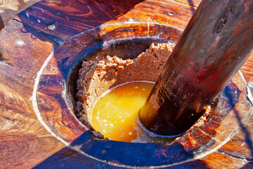 an old traditional wooden oil mill filled with golden peanut oil