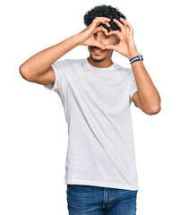 Young arab man wearing casual white t shirt doing heart shape with hand and fingers smiling looking through sign