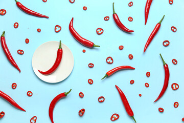 Plate with fresh chili peppers on blue background