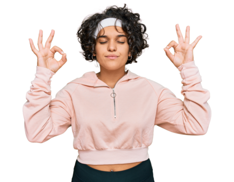 Young hispanic woman with curly hair wearing sportswear relax and smiling with eyes closed doing meditation gesture with fingers. yoga concept.