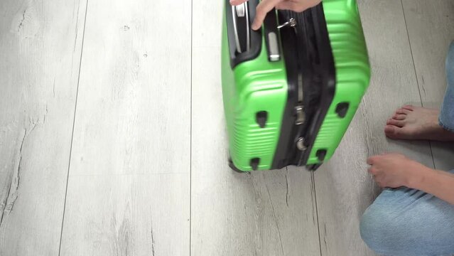 Guy rotate the green baggage case with clothes in hand