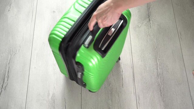 Guy rotate the green baggage case with clothes in hand