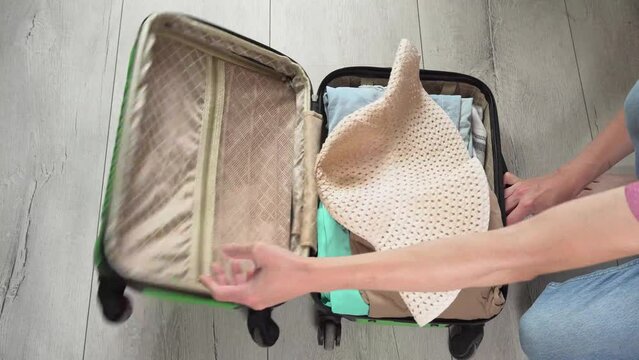 Guy opens the green baggage case and puts clothes in