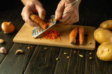 Cooking carrot salad with the hands of a chef on the kitchen table. The process of preparing a...