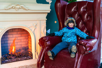 A cheerful boy on a fairy-tale throne at a Christmas market. New Year's entertainment.