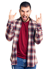 Young handsome man wearing casual shirt shouting with crazy expression doing rock symbol with hands up. music star. heavy music concept.