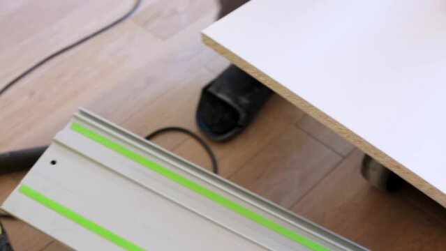 Man cleans edge of board after cutting it with circular saw.