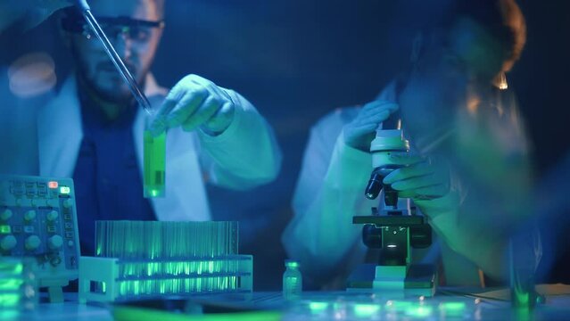 Scientists are analyzing samples in medical research laboratory. Scientific searching for vaccine with microscope to treat diseases in medicine. Pharmaceutical Lab and biotechnology development