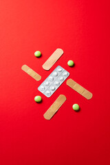 Overhead View of Medication and Bandages on vivid Red Background, common symbol in healthcare