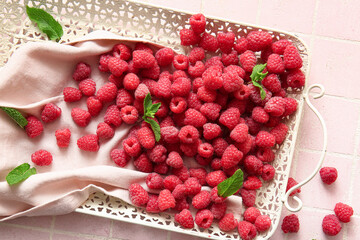 Tray with fresh raspberries and mint on pink tile background